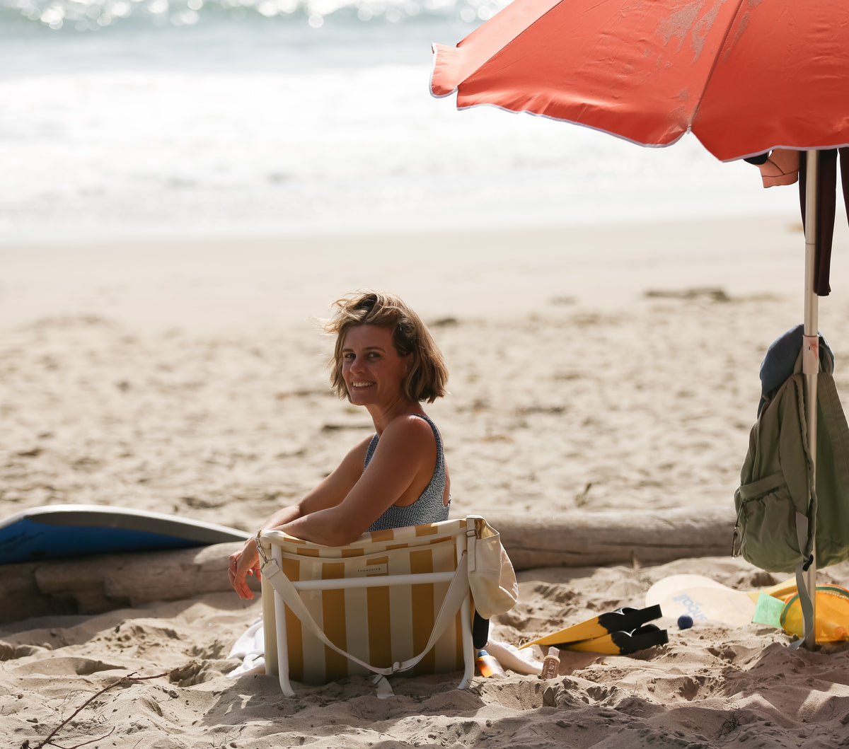 Dresden Holden santa Barbara based acupuncturist specializing in fertility and maternity acupuncture pictured at Bates beach Rincon sitting a beach chair with an orange umbrella and boogie board