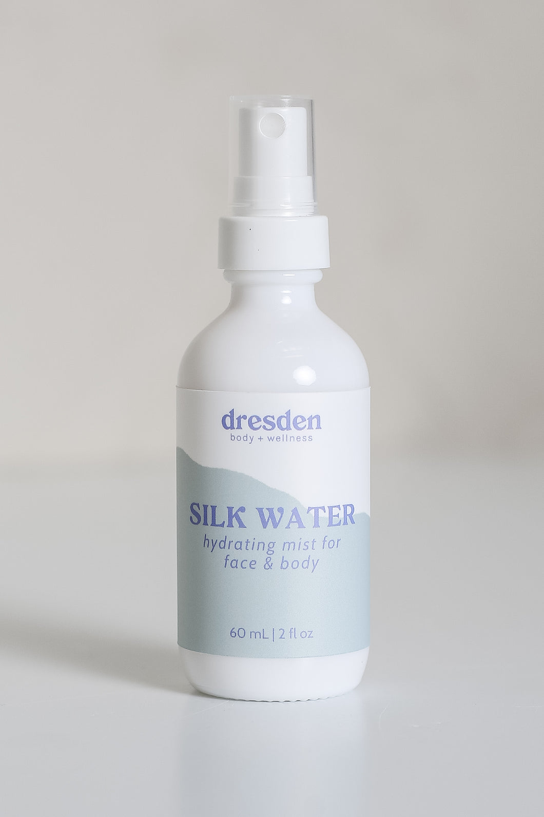 Dresden Holden Acupuncturist in Santa Barbara Ca made Silk water a hydrating toner with organic hydrosols, niacinamide, glycerin, silk amino acids, and is pH balanced to hydrate and heal the skin barrier, in a 2 ounce white glass bottle with a label written in blue font
