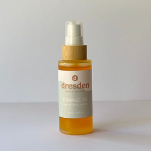 Dresden Body + Wellness orange oil in glass bottle with bamboo serum pump top, belly and body oil, orange color